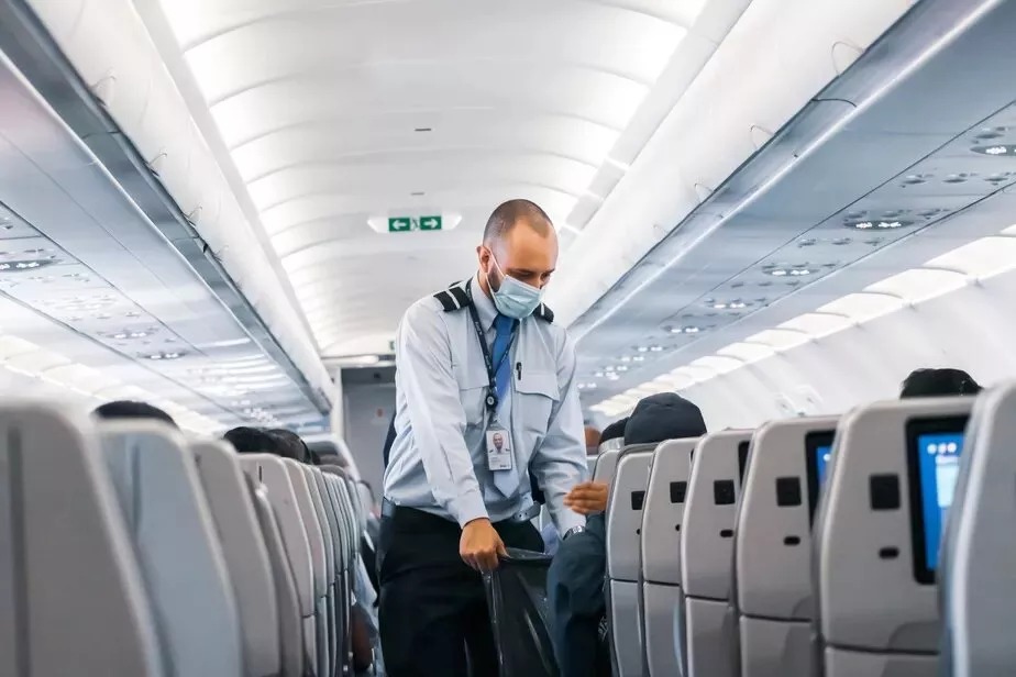 Comissário de bordo de máscara em avião - Foto: Unsplash